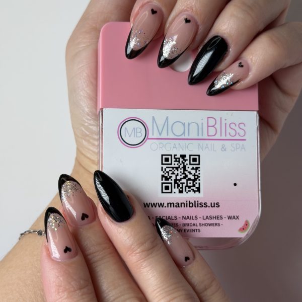 Black French tip almond nails with silver holographic glitter and heart accents by ManiBliss Organic Nails and Spa